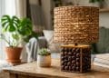 Handmade oil palm waste used lamp project with woven palm fiber shade and palm kernel shell base glowing on a wooden table